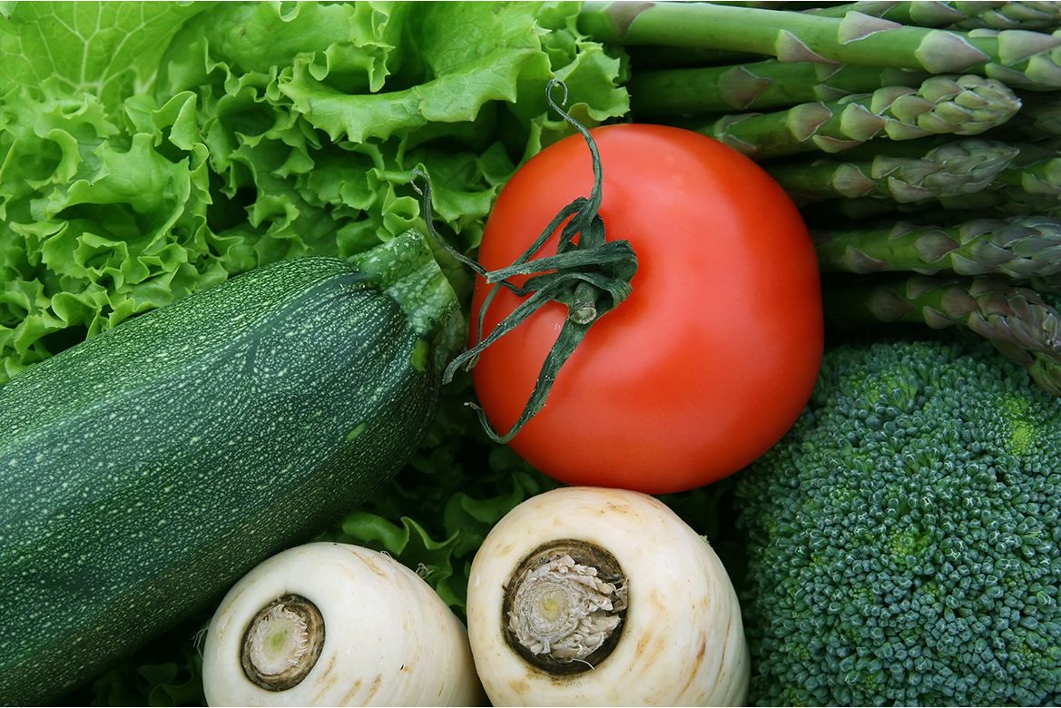 Fresh vegetables arranged together, including lettuce, zucchini, tomato, asparagus, broccoli and turnips.