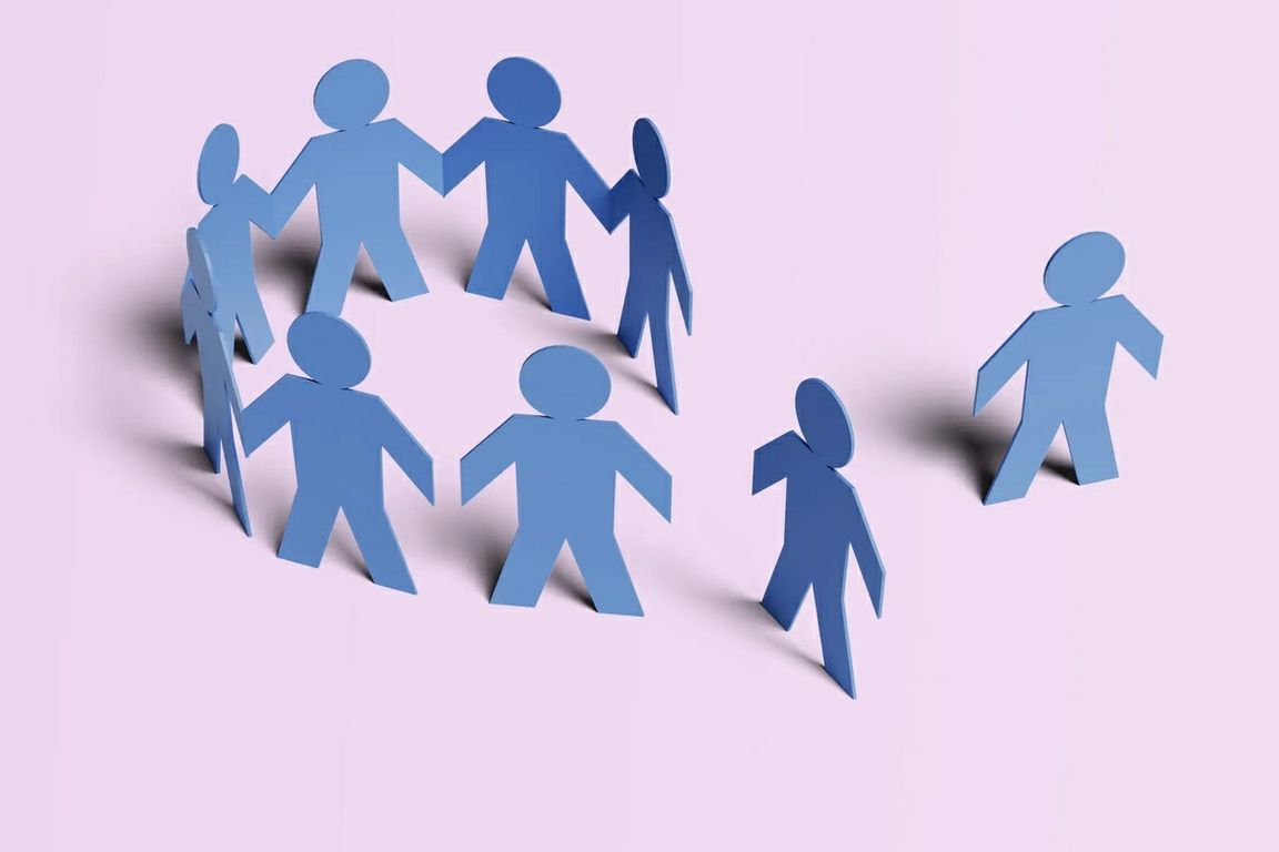 Illustration of blue paper figures, with several forming a circle while two others stand apart from the group.