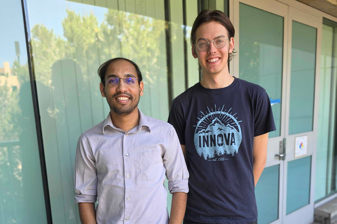 Soumitra Athavale, left, and Justin Manoff stand side by side outside a building with glass windows and doors; Athavale wears a button-down shirt, Manoff a graphic T-shirt.