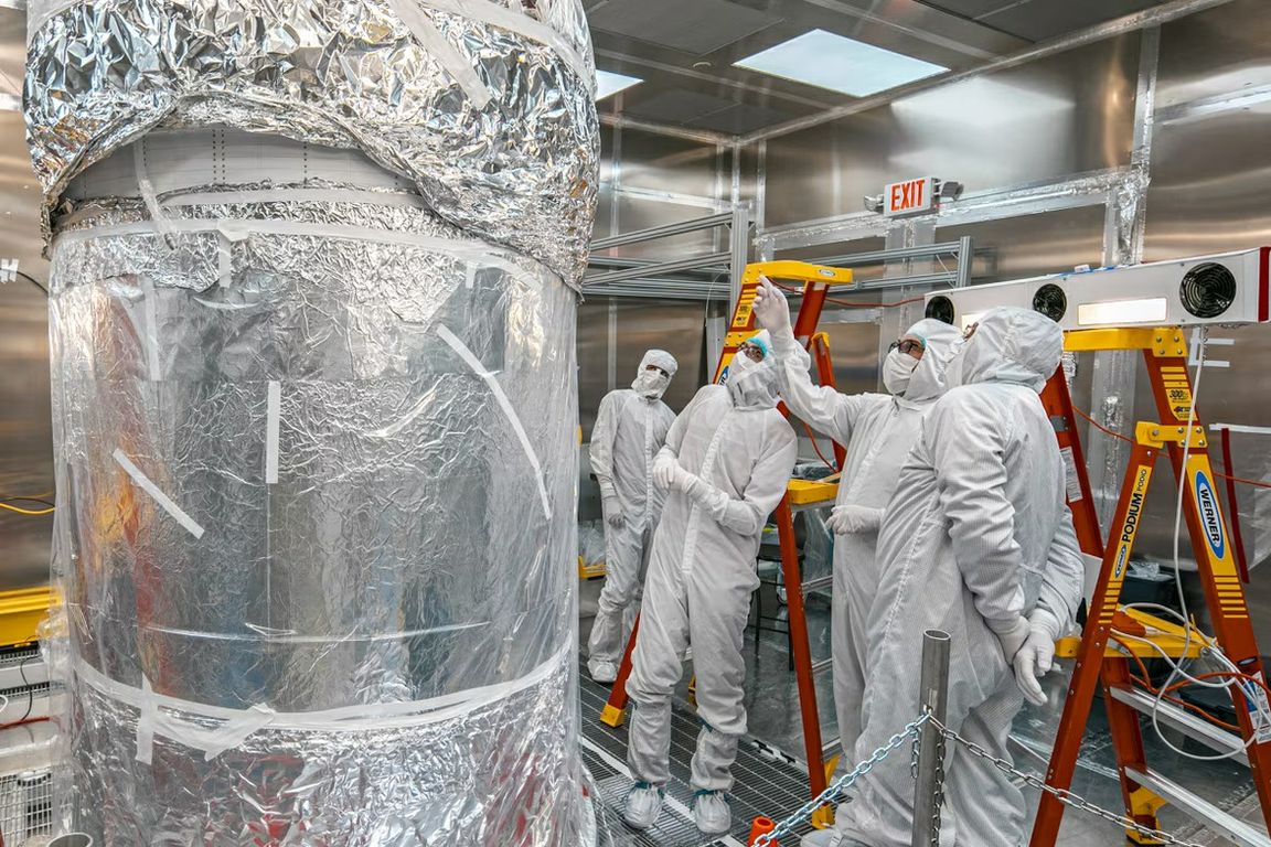 Researchers in protective suits assess the LZ experiment’s central detector, an instrument designed to search for dark matter candidates.