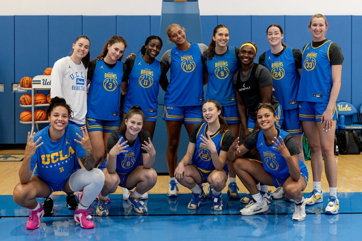 Members of the UCLA women’s basketball team pose together on the court during preseason practice