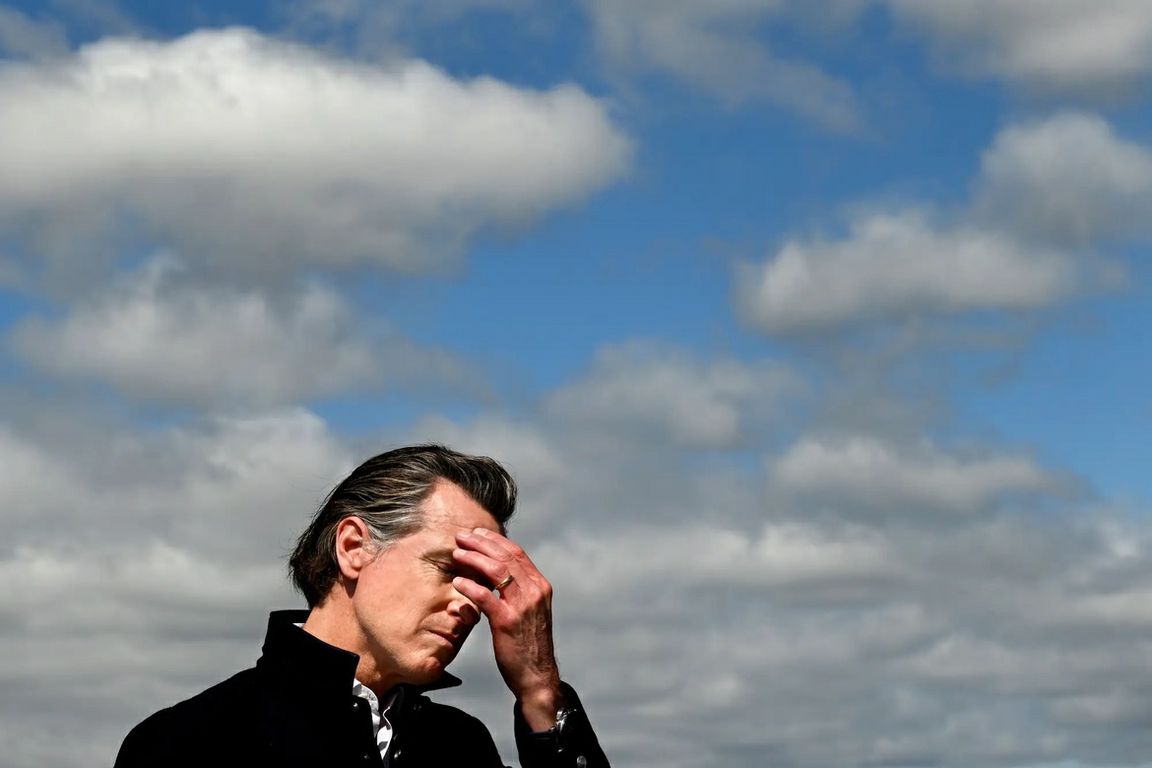 California Gov. Gavin Newsom closes his eyes and presses a hand to his forehead during a March 2023 news conference in Pajaro addressing severe flooding caused by a series of atmospheric rivers.
