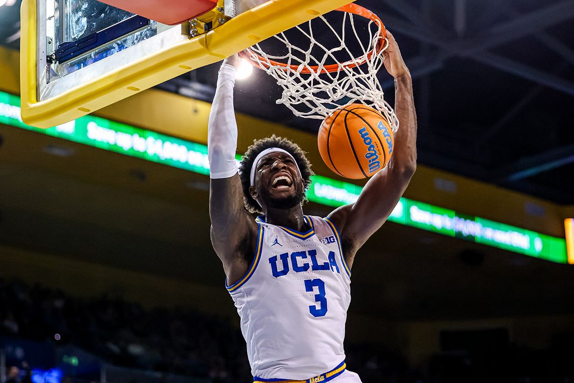UCLA Basketball player dunking the ball into the net with an intense expression on his face.