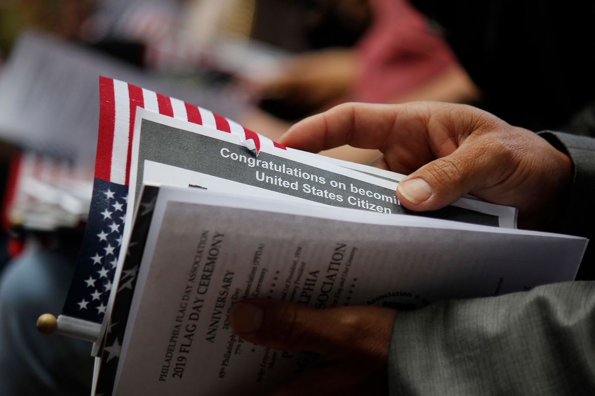 A person holds a U.S. citizenship congratulatory card and printed documents during a naturalization ceremony.