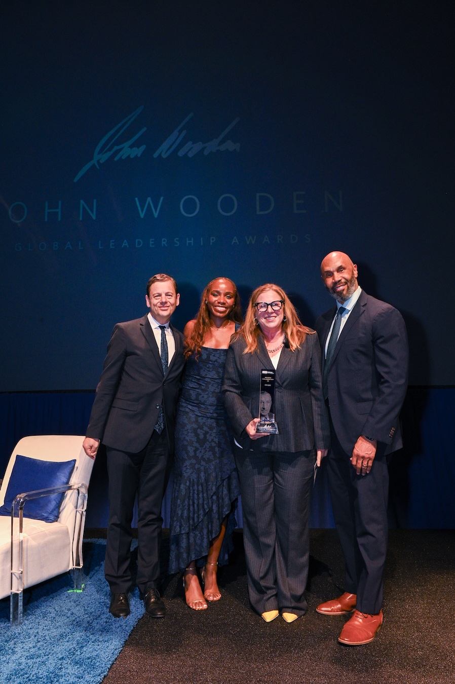 From left, Gareth James, Charisma Osborne, Cori Close and Darnell Hunt pose together onstage, smiling as Close holds her glass leadership award.
