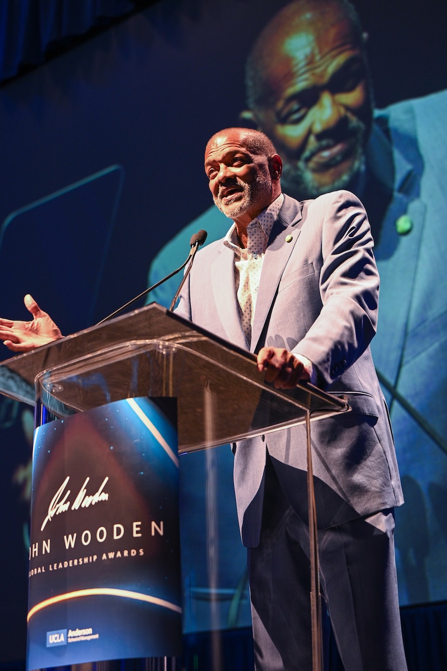 Marques Johnson gestures while speaking at a clear lectern during the John Wooden Global Leadership Award ceremony.