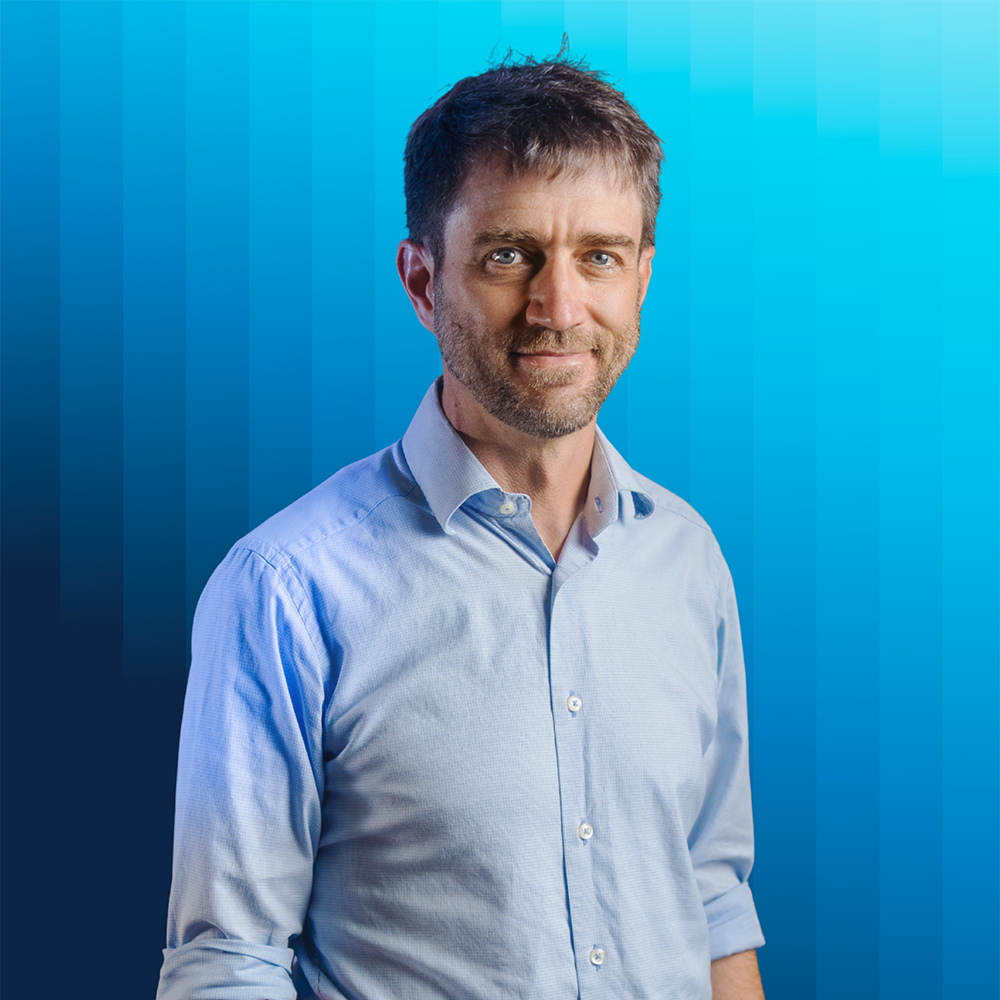 Portrait of Wesley Campbell in light blue button-down against a blue background.