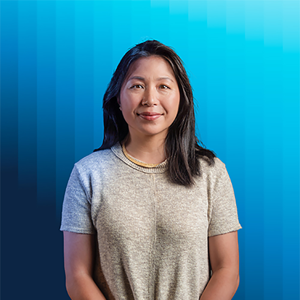 Portrait of Elaine Hsiao in gray top against blue background.