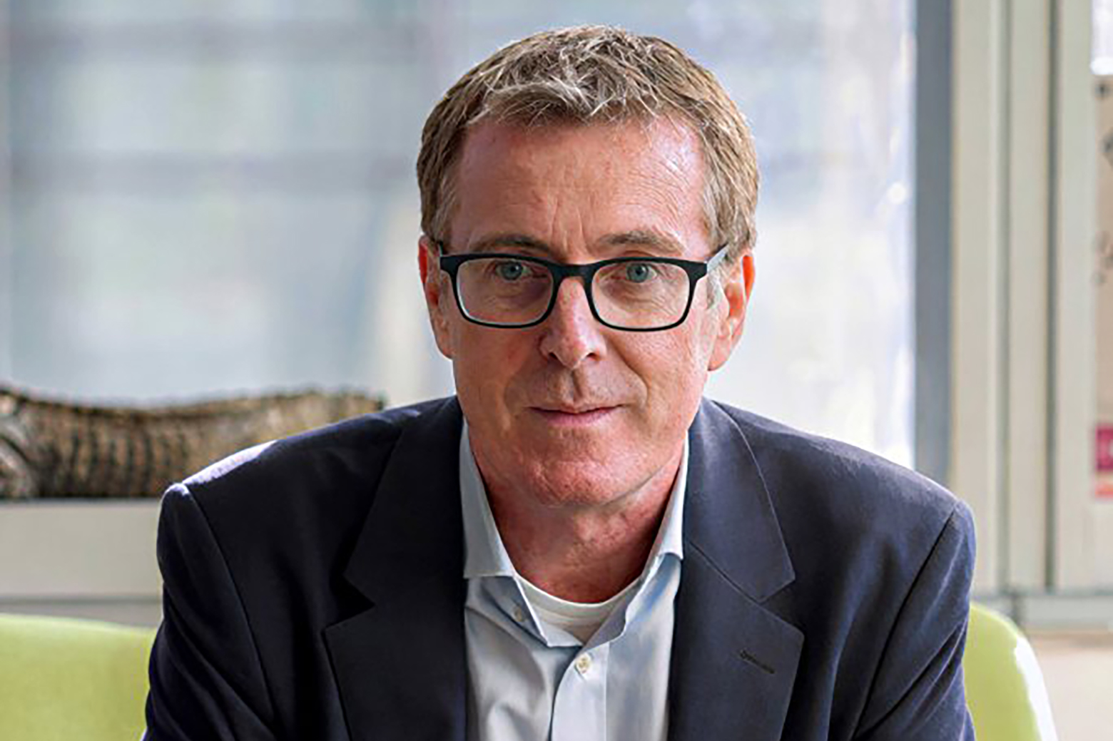 Headshot of David Artis wearing glasses, light blue button-down and dark blue jacket.