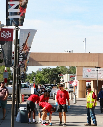 Working to help beautify main campus before the start of the fall semester, members of UNM's football team pull weeds near Parking and Transportation. Cleanup near PATS