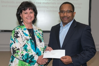 Edmond Hughes (right), vice president of human resources and administration at Ingalls Shipbuilding, presents a $5,000 grant to Robin Fenton, state director of Friends of BEST (Boosting Engineering, Science and Technology) in Alabama. The Jubilee BEST Robotics Program was one of 28 projects to receive an Ingalls STEM grant this year. Photo by Andrew Young/HII Friends of BEST Receives STEM Grant from Ingalls Shipbuilding