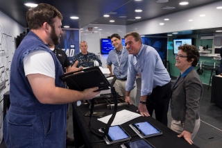 Aaron Wikle (left), a foreman at Newport News Shipbuilding, demonstrates digital shipbuilding technology for Sen. Mark Warner inside a trailer the shipyard uses for training and recruiting next-generation shipbuilders. Also pictured (left to right) are Capt. Jason Lloyd, commanding officer, Supervisor of Shipbuilding, Conversion and Repair, Newport News; Tim Sweitzer, Newport News’s director of digital shipbuilding; and Newport News Shipbuilding President Jennifer Boykin. Photo by John Whalen/HII Newport News Shipbuilding Hosts Sen. Mark Warner