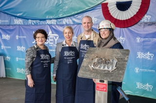 Jess Batruk, a Newport News Shipbuilding welder originally from New Jersey, displays the welded initials of Susan DiMarco, the sponsor of submarine New Jersey (SSN 796). Also pictured (left to right) are Jennifer Boykin, president of Newport News Shipbuilding; DiMarco; and Cmdr. Joseph Spinks, the submarine’s commanding officer. Photo by Ashley Cowan/HII New Jersey (SSN 796) Keel Authenticated