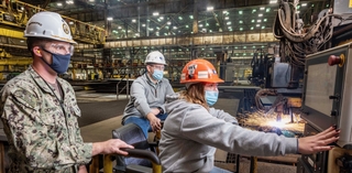 Erika Lynd, Ingalls burner workleaderman, cuts steel into patterns using the Avenger IV plasma cutter, signifying 100 tons of steel cut and start of fabrication for the destroyer Jeremiah Denton (DDG 129). Observing the milestone are U.S. Navy Cmdr. Sean Doherty, DDG program manager’s representative, and Ben Barnett, Ingalls Shipbuilding’s DDG 129 ship program manager. Photo by Derek Fountain/HII Jeremiah Denton (DDG 129) Start Fab