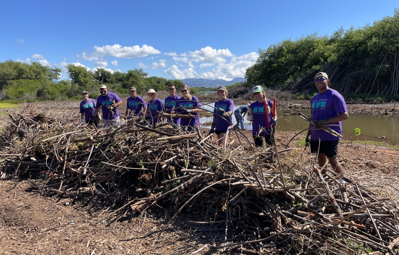 Team Kōkua and HAVEN members at Puʻuloa behind a pile of overgrowth they removed from the stream's edge. IMG_0432