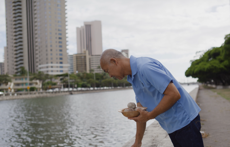 Nago, shown peering into a toss site along the Ala Wai, says the difference in water quality is noticeable by the naked eye. hiro