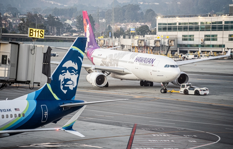 A Hawaiian Airlines Airbus A330 pulling into San Francisco International Airport alongside an Alaska Airlines aircraft. SGO ASHA Lobby