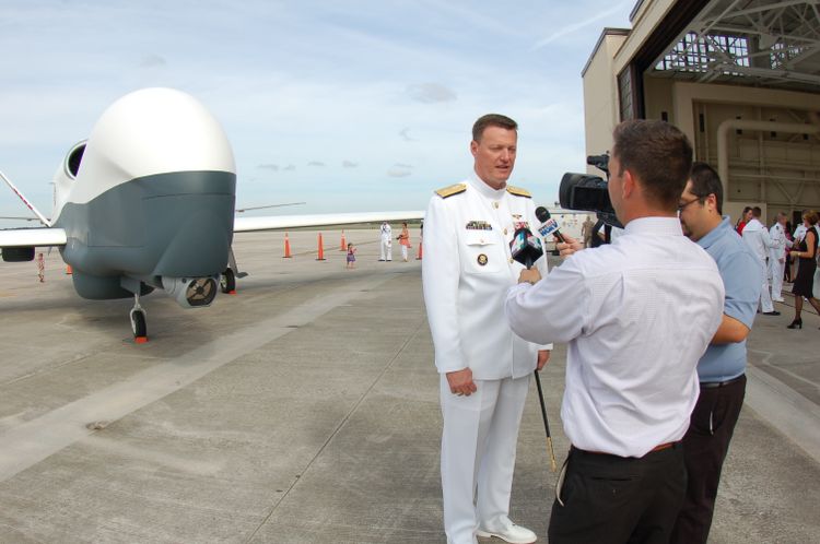U.S. Navy Rear Admiral Kyle Cozad speaks to a local Florida news station in front of a full-scale Triton model at the commissioning of VUP-19. Triton Soaring Toward Operational Status