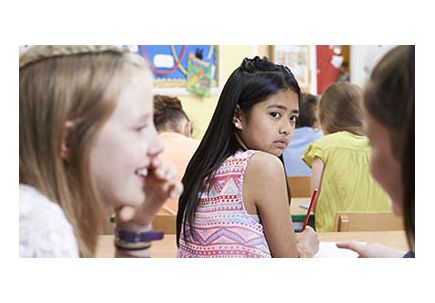 Unhappy Girl Being Gossiped About By School Friends In Classroom