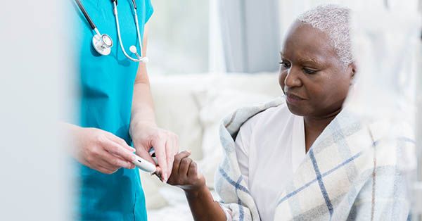 Home healthcare nurse checks patient's blood sugar