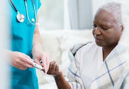 Home healthcare nurse checks patient's blood sugar
