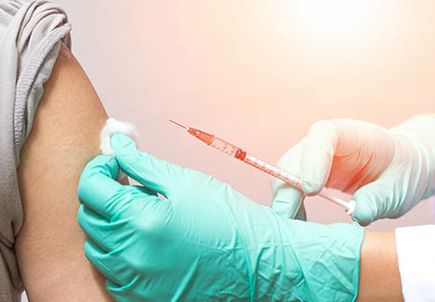 Vaccination healthcare concept. Hands of doctor or nurse in medical gloves injecting a shot of vaccine to a man patient