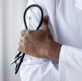 Male african doctor wear medical coat holding stethoscope, close up