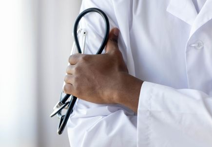 Male african doctor wear medical coat holding stethoscope, close up
