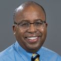 Christopher Evans, M.D., smiling, is wearing a blue shirt, yellow tie and eyeglasses. (OHSU)