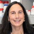 Marina Wolf, Ph.D., has long dark hair, smiling in a lab setting.
