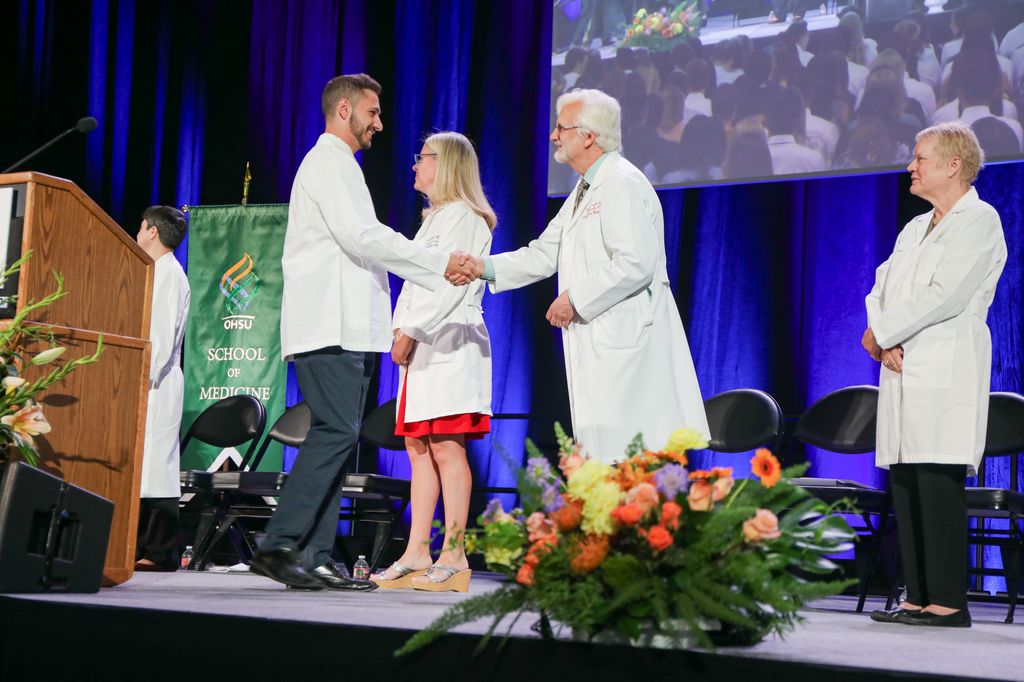 El Dr. David Jacoby, decano y profesor de medicina, fisiología y farmacología en la OHSU School of Medicine, felicitó a los nuevos estudiantes de medicina después de ponerse los guardapolvos blancos por primera vez en la Ceremonia de los guardapolvos blancos del 11 de agosto de 2023. (OHSU/Christine Torres Hicks)