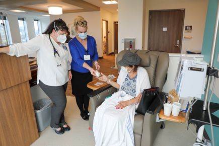 La enfermera con práctica médica Sandra Youngworth, D.N.P., a la izquierda, y la coordinadora de investigaciones médicas Vicki Abtin asisten a la paciente Rhonda Stranz durante una cita el 9 de octubre. (OHSU/Christine Torres Hicks)