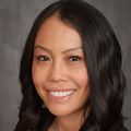 Laura K. Chan, Pharm.D., M.P.H. has wavy, smooth long black hair, smiling against a gray background.
