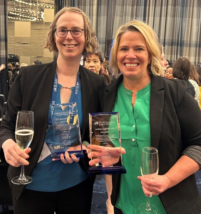 Shelley Tworoger, Ph.D., left, has short curly blonde hair, eyeglasses, holding a wine glass, and Andrea Cedfeldt, M.D. has short blonde hair, smiling; both at a conference social setting.