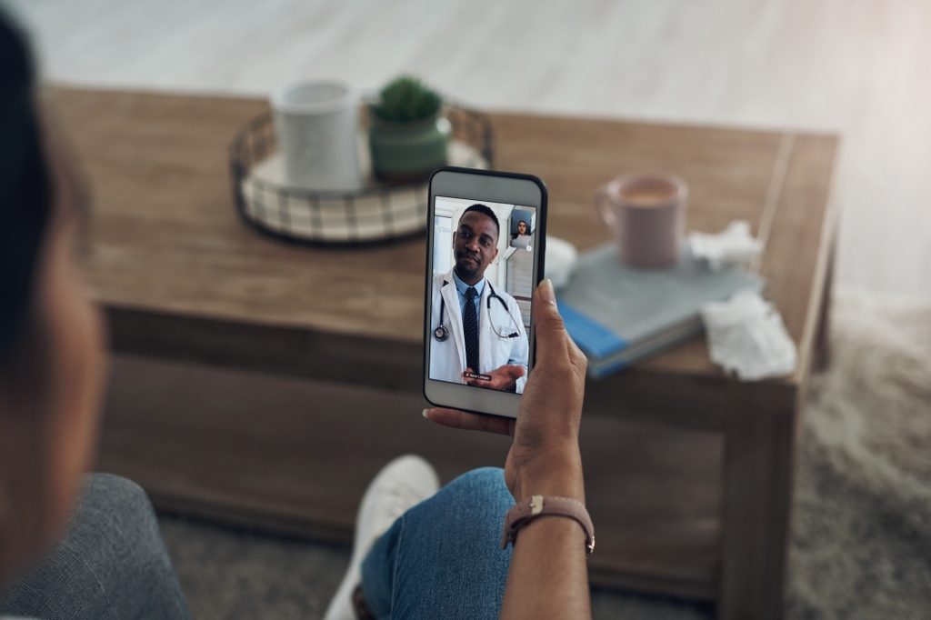 Image is of a patient who is using their cellphone at home to have a telehealth visit with a doctor. New research led by OHSU finds that the use of telehealth, combined with outreach by peers with lived experience in illicit drug use, dramatically boosts the diagnosis and curing of hepatitis C, the most common blood-borne virus in the United States.