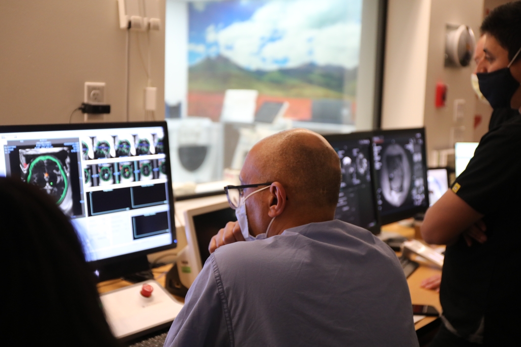 El doctor Raslan se sienta junto a una computadora en una sala de control y realiza cirugías cerebrales sin incisiones en OHSU. OHSU es el único centro en Oregón y acaba de convertirse en el primero del mundo en ofrecer la versión optimizada de la tecnología de ultrasonido focalizado de alta frecuencia a pacientes que sufren temblor involuntario incapacitante. (OHSU/Christine Torres Hicks)