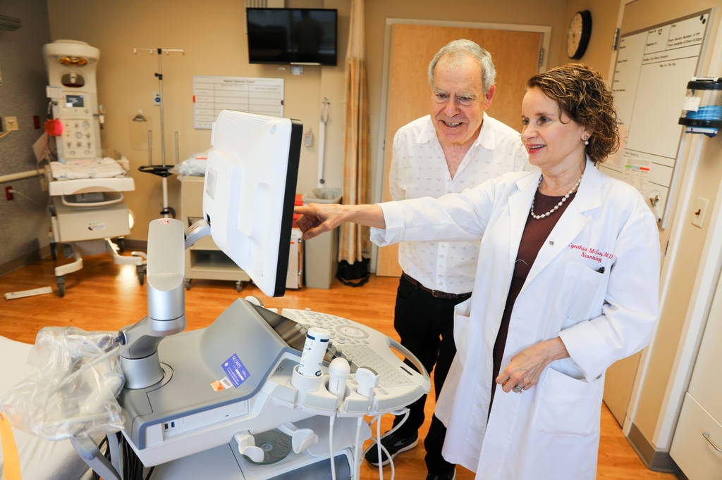 La foto es de Cindy McEvoy, derecha, y Eliot Spindel, izquierda, mirando una pantalla de computadora llena de datos en una sala de partos de OHSU. En la investigación continua de OHSU sobre cómo mitigar los efectos del tabaquismo en el desarrollo fetal, los Dres. Eliot Spindel, Ph.D. y Cindy McEvoy, hallaron que la suplementación de vitamina C mejora el flujo sanguíneo de la placenta al feto en fumadoras embarazadas, y lo acerca a los niveles que se ven en personas que no fuman. (OHSU/Christine Torres Hicks)