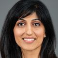 Ruchi Thanawala, M.D., M.S., has long, straight dark hair, white top, and smiling against a gray background.