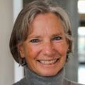 Jackie Shannon, Ph.D., has cropped gray hair and wearing a gray sweater, smiling in the hall of the Knight Cancer building.