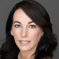 Bridgette Bochner, Ph.D., RN, CNE, has long dark, wavy hair, a black top with a dark gray background.