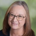 Mary Zelinski, Ph.D. (OHSU) has long brown hair and wears glasses, smiling against a green background.