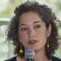 Honora Englander, que tiene cabello castaño rizado hasta los hombros y viste una blusa negra con pantalones negros, se sienta en la reunión del panel de información sobre fentanilo en OHSU.