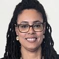 Raina Croff, Ph.D., center, has long braided hair pulled back from the top, glasses, wearing a white top, black blazer and black pants, smiling with two award presenters at the conference.