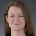 Colleen Cowdery, M.D. , has long light brown hair, wearing a red top and black blazer, smiling against a gray background.