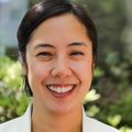 Katherine Jorda, M.D., tiene el pelo corto y oscuro y lleva una bata blanca de médico mientras sonríe en el jardín del Centro para la Salud de la Mujer de OHSU.