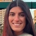 Paula Sanchez Molina, Ph.D., has long, straight brown hair, and a multicolor sweater, smiling outside.
