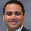 Salman Hirani, M.D., has short, wavy dark hair, wearing a suit, smiling.