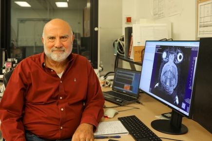 Martin Pike tiene el pelo corto y gris y una camisa de vestir granate, y está sentado frente a una computadora que muestra datos de la investigación.