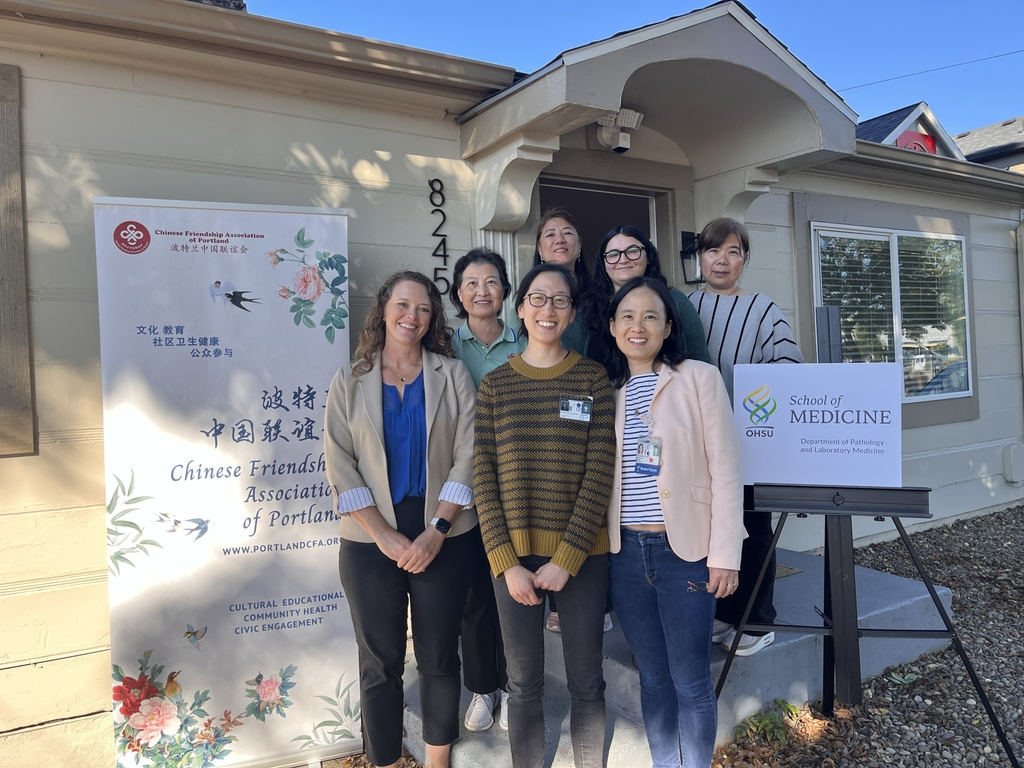 Image is of several people standing in front of a building.