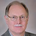David Farrell, Ph.D., F.A.H.A., has thin, short grayish brown hair, eye glasses, a gray mustache and a gray suit.